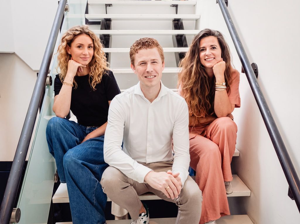 Drie teamleden van Het Miles College zitten lachend op de trap van de school